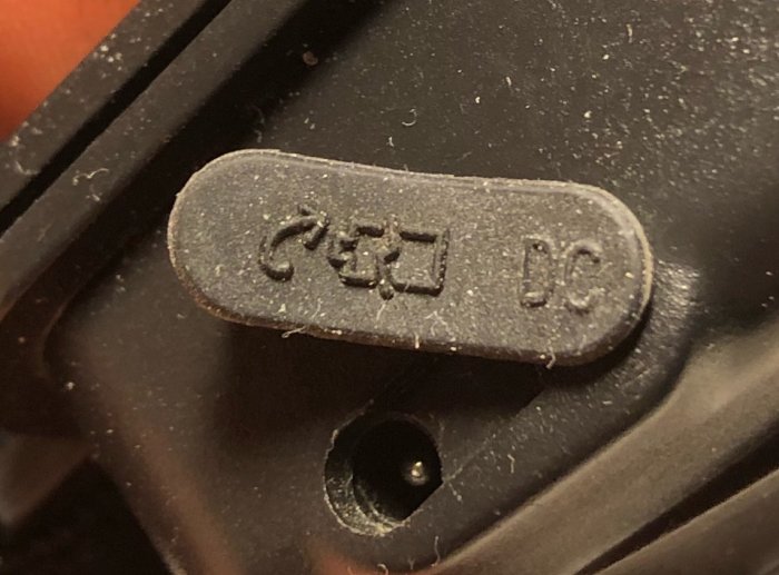 Närbild på en svart plastdetalj med texten "CEJ DC" i relief.