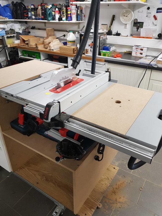 En verkstadsbild som visar en träfräsinstallerad på ett arbetsbord med dammutsug kopplat, i ett organiserat verkstadsrum.