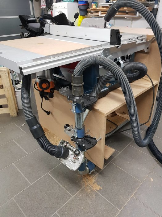 Träfräs monterad på arbetsbänk med justerbar arm och anslutna dammsugar slangar.