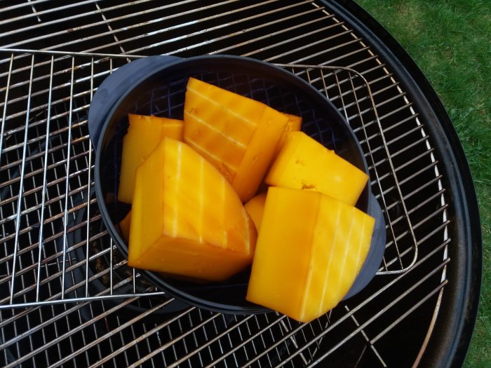 Bitar av cheddarost på en rökgrill redo för rökning.