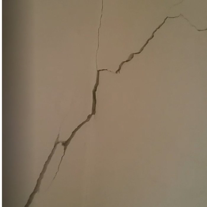 Sammanhängande spricka i en vägg som sträcker sig ungefär 1,5 meter och är 1-3 cm bred.