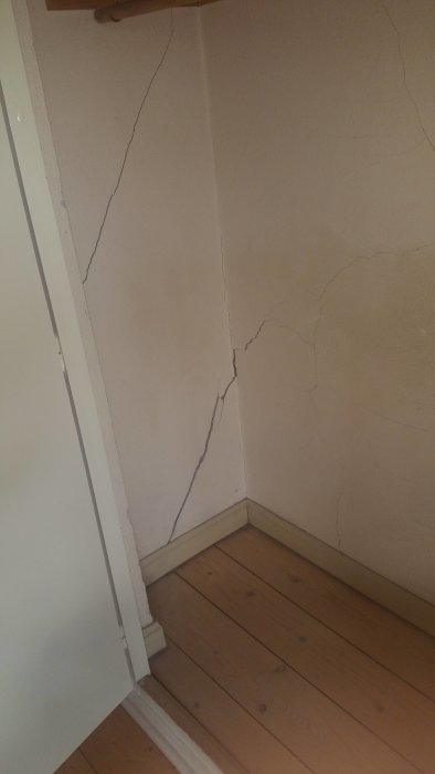 Sprickor i en hörnvägg och tak i en lägenhet, tecken på potentiella sättningsskador från 30-talet.
