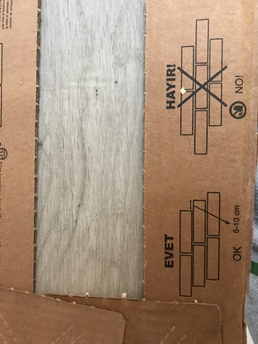 Träklinkerplatta bredvid kartong med instruktioner för läggning, nej till halvförband och ja till 6-10 cm förskjutning.