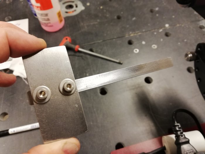 Hand håller ett uppgraderat sidoanhåll av aluminium med PTFE-tejp för låg friktion medan ett slipat verktygsstål syns.