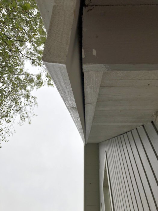 Närbild på en skålning av nedre vindskiva nära en fyrkantig bräda, som visar en glipa i en byggnadskonstruktion.