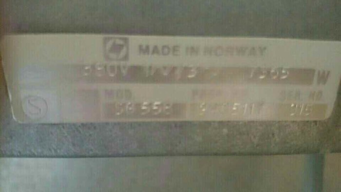 Suddig bild på en etikett med texten "MADE IN NORWAY" och specifikationer för en elektrisk komponent.