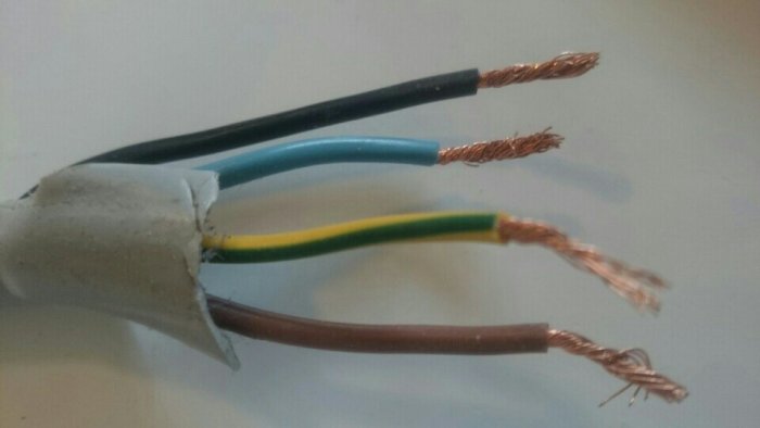 Gammalt elektriskt spisuttag som visar uråldriga svarta ledare, behov av uppdatering.