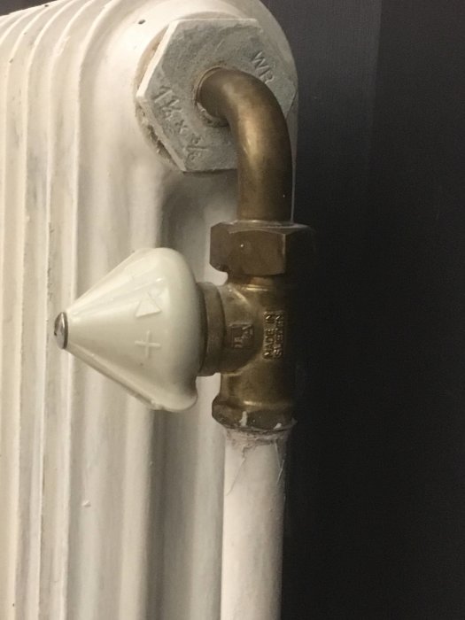 Gammaldags radiatorventil av mässing med vred i porslin.