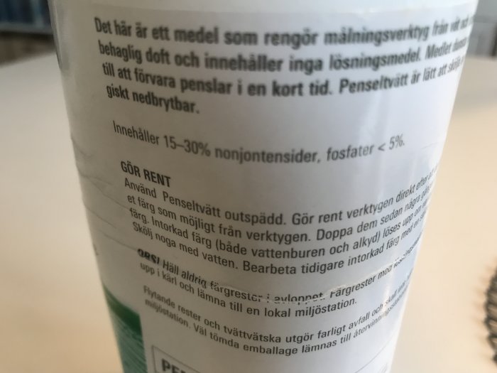 Närbild på en penseltvättsbehållare med instruktioner för rengöring av målningsverktyg.