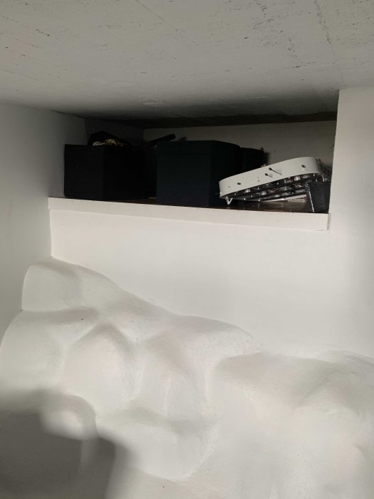 Halvvägg av lättbetong ovanför lösa stenar i en källare under renovering.