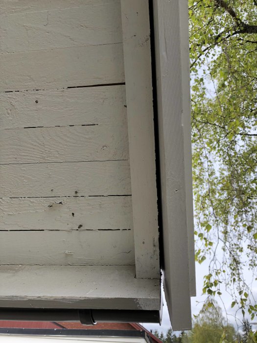 Skewed fascia board with visible gap and discoloration against wooden siding, possible installation issue after roof work.