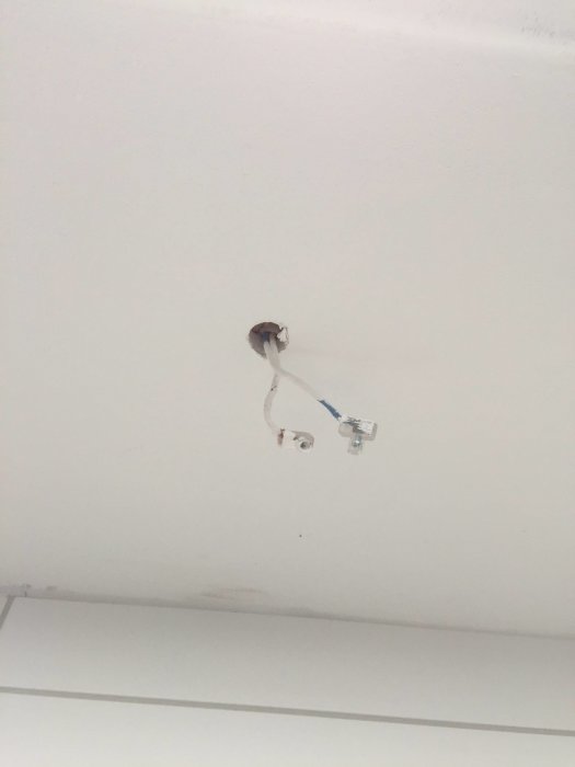 Kopplingadosa i tak med en skruv i mitten och ledningar som sticker ut, ritad för installationshjälp.