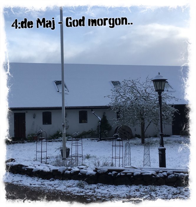 Hus och trädgård täckta av oväntad snö i maj, med texten "4:e Maj - God morgon.