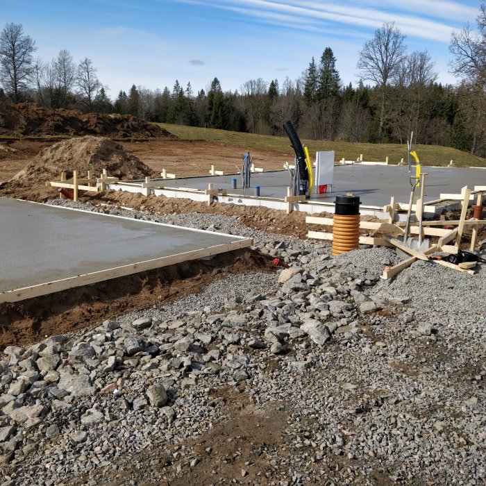 Gjuten betongplatta och förberedelser för husbygge med skog i bakgrunden.