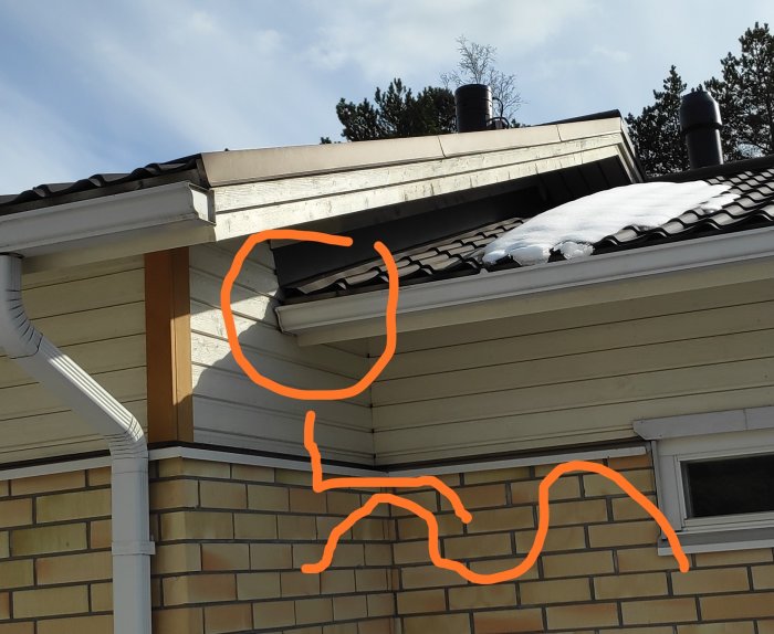 En del av ett hus med snö på taket, markerad vindflöjel vid takfoten som pekar på potentiellt problemområde för ventilation.