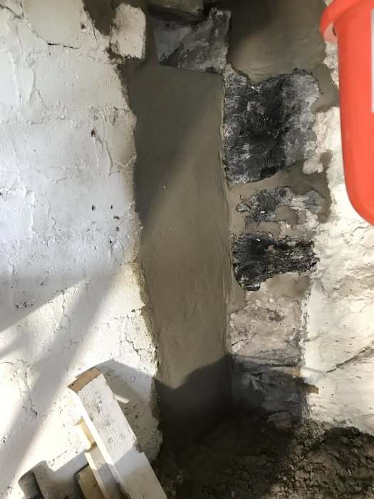 Nyputsad innervägg med ojämn struktur och synliga lagningar väntar på målning.