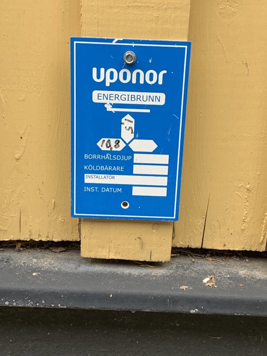 Skylt för Uponor energibrunn på vägg med information om borrhålsdjup och kylbärare relaterat till bergvärme.