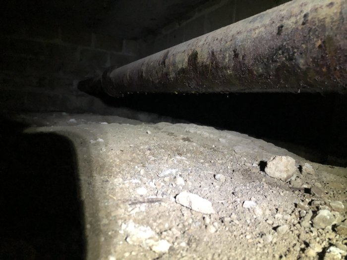 Gamla rostiga röret med droppar på undersidan i mörkt utrymme.