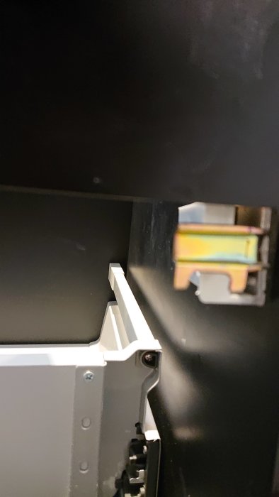 Fästplatta på en kommod nära synlig skruv, fokuserar på upphängning för installation.