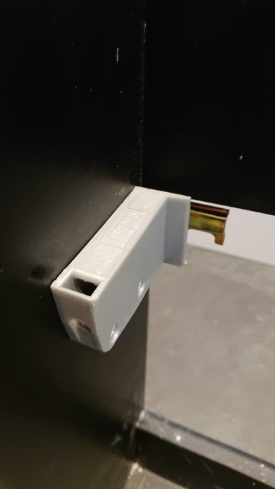 Fästbeslag för kommod nära en svart vägg, fråga om montering i badrum.
