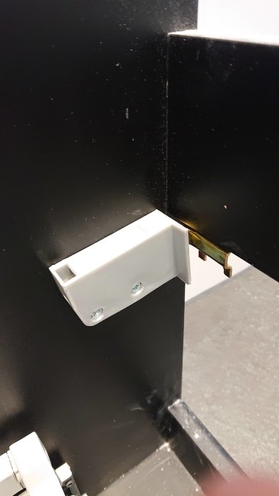 Fästen på en svart kommod som förbereds för montering på ett badrumsskåp.