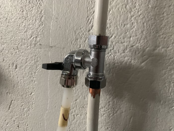En ballofix ventil plomberad på en varmvattenledning, installerad på en vitmålad vägg.