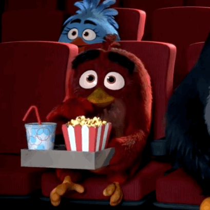 Animerade karaktärer från Angry Birds ser på bio, en röd fågel håller i popcorn och en läsk.