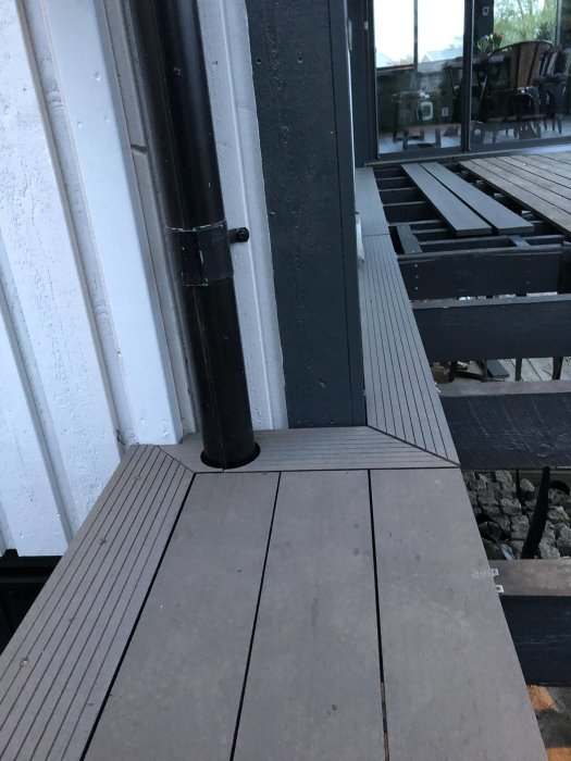 Pågående arbete med en komposittrall bredvid en vit husvägg och kantsten längs en trädgårdstomt.