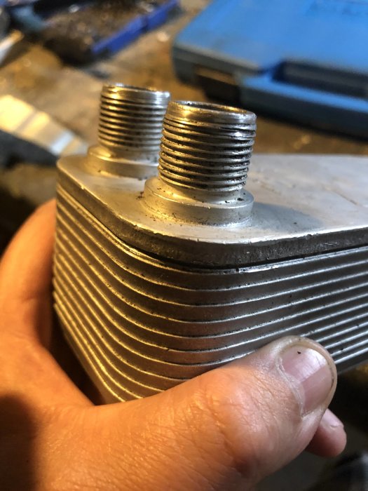 Närbild av oljekylare med 19mm gängade anslutningar som hålls i en hand.