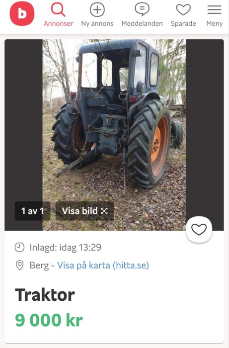 Bakifrånvy av en använd blå traktor med stora hjul parkerad utomhus.