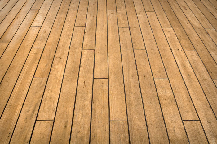 Ett skeppsgolv i trä med markerade plankor och skarvar, utstrålar värme och hållbar kvalitet.