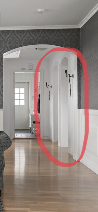 Interiör med rödmarkerade rundade dörröppningar till kök och sovrum i ett hus.