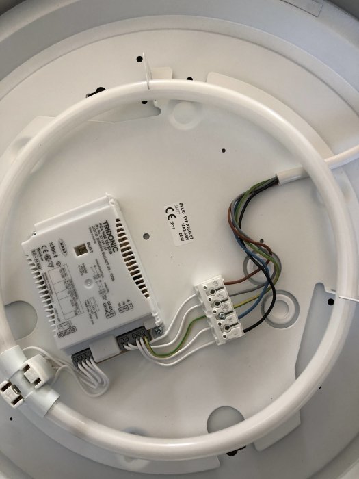 Bild på en öppen lampa med uppkopplad driver och flera kablar synliga, tidigare ansluten till dimmer.