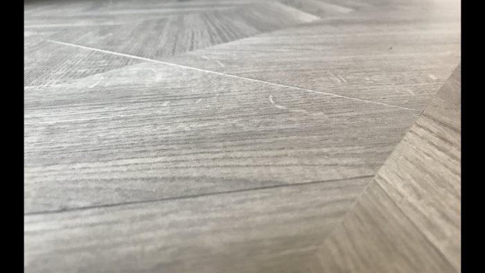 Närbild på Tarketts laminatgolv med ojämna skarvar och nivåskillnader.