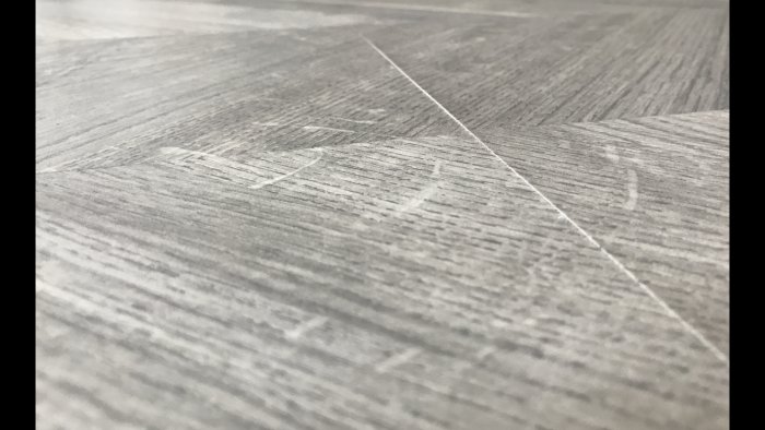 Närbild på Tarketts laminatgolv LaminArt "Manor Oak Vogue" med synliga och kännbara ojämnheter vid skarvarna.