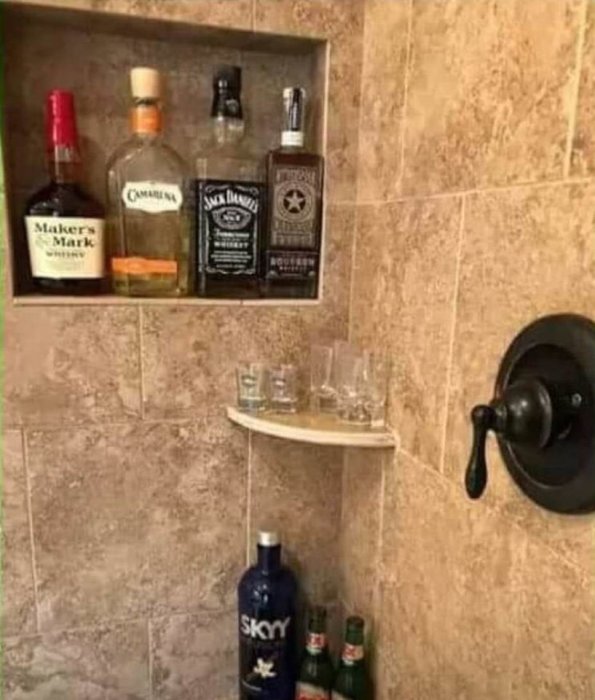Inbyggd hylla i dusch med whiskyflaskor och drinkglas som humoristisk tolkning av doktorsråd.