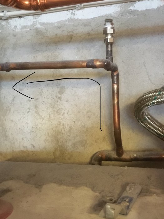 Kopparledningar och rör runt en bergvärmepump med en markerad svacka och propptillslutet rör.