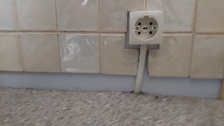 Ett perilexuttag på en kaklad vägg, avsett för att ansluta en spis.