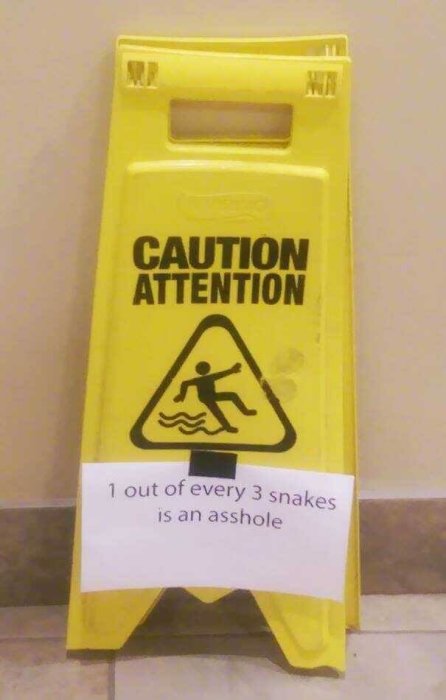 Varningsskylt med texten "CAUTION ATTENTION" och en pape-lapp med text "1 out of every 3 snakes is an asshole