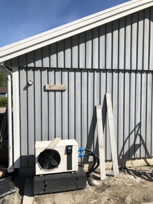 Bräda uppskruvad 30 cm över husets ordinarie takhöjd bredvid värmepump och lösa plankor.
