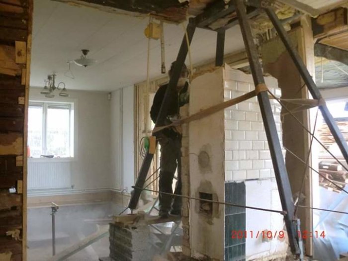 Renovering inne i hus: person monterar stödstruktur runt halvmonterad skorsten.