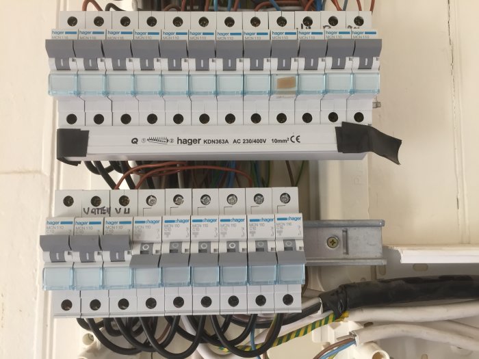 Öppen elektrisk Hager-central med säkringar och kablar, vissa med elektrikertejp, under renovering.