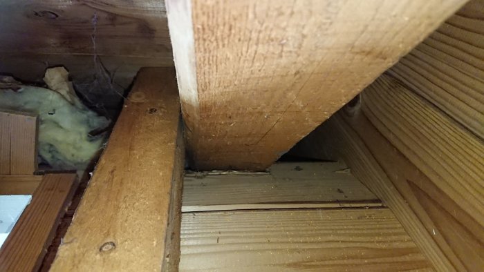 Träkonstruktion på vind med reglar och isolering, tecken på renoveringsbehov och konstruktionsfrågor.