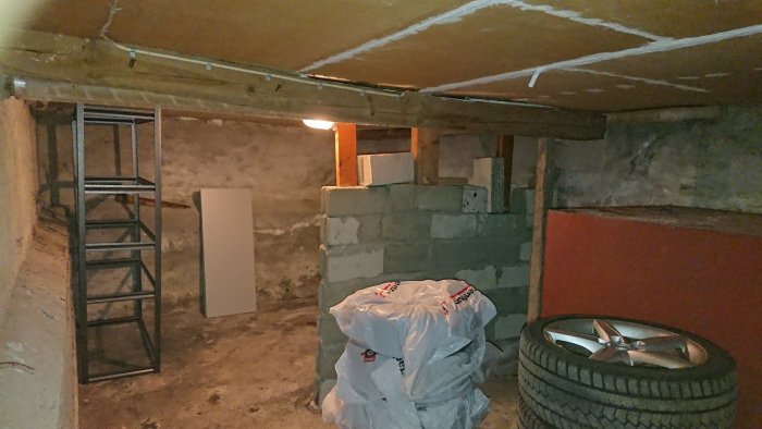 Bild av en källarlokal i ett äldre hus med synliga träbalkar, betongblock och oavslutad konstruktion.