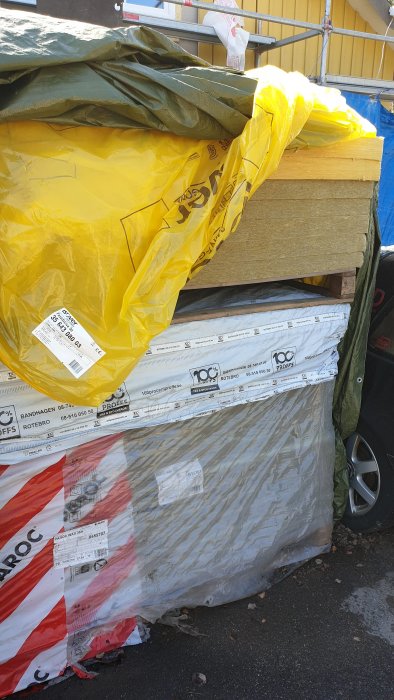 Opackade isoleringsskivor från Paroc och Isover staplade utomhus.