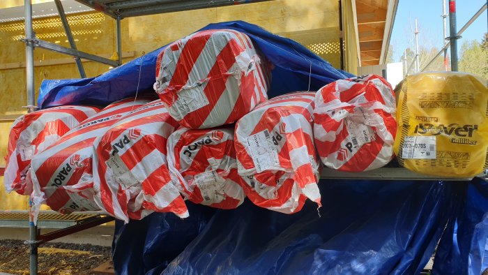 Balar av isolering från Paroc och Isover upplagda på blå presenning.