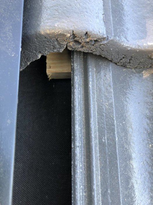 Närbild på felaktigt monterad kantpanna och kapad bärläkt på ett tak, risk för fallande byggmaterial.