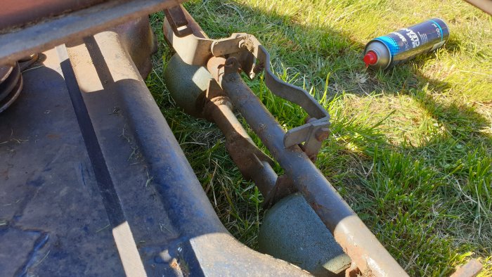 Närbild på hjulinställningen på klippbordet till en gräsklippare med sprayburk i bakgrunden.