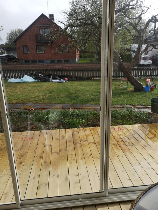 Utsikt genom glaspartier till ett pågående byggprojekt av ett uterum med platsbyggd trätrall.