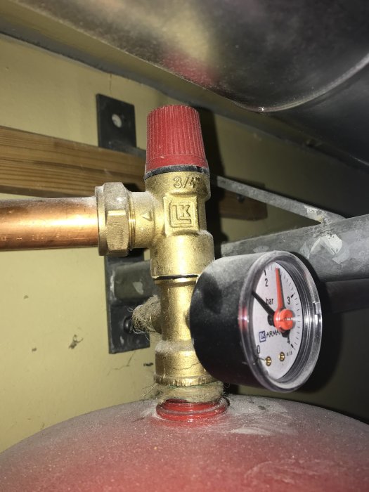 Installationsdetalj av en FTX-enhet med 22 mm kopparrör, klämringskoppling och manometer på ett expansionskärl.